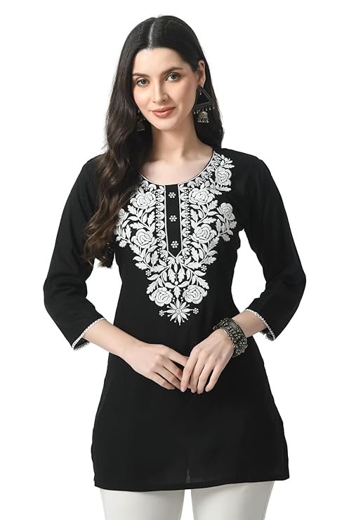 Black Chikankari Kurti for Women | Lucknowi Embroidered Short Kurta A woman models a black, three-quarter sleeve short kurti featuring dense, white floral and leaf Lucknowi Chikankari embroidery around the neckline.