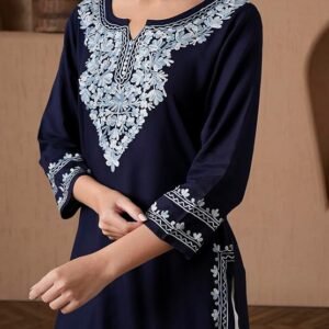Full-length image of a woman wearing a navy blue straight-cut kurta with heavy white and light blue Kashmiri Aari embroidery on the yoke, cuff, and hem, paired with pleated white Patiala salwar pants.